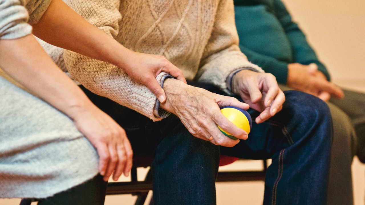 An elderly man being assisted by a woman, representing the effect of COVID on long-term care homes